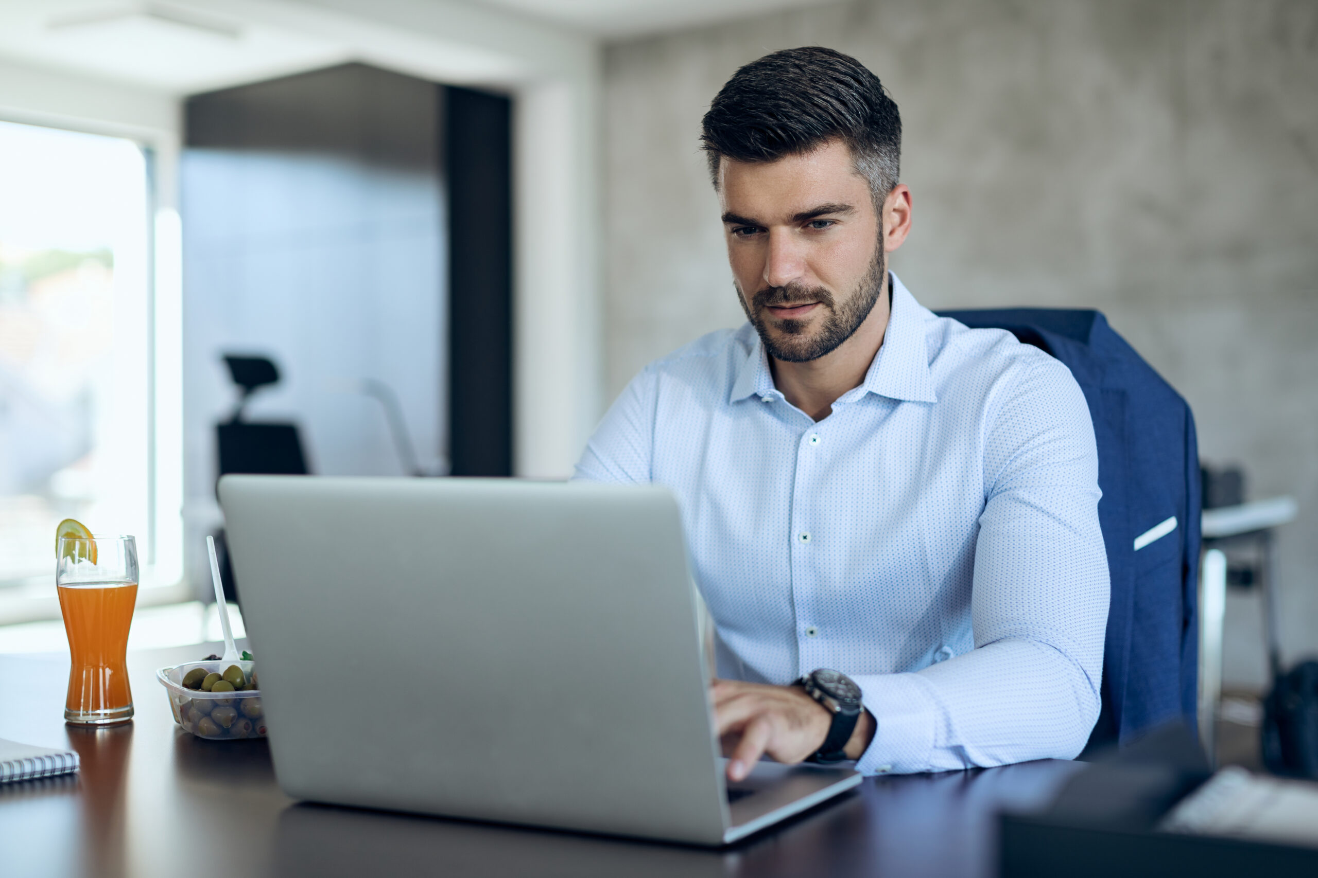 Young businessman working on laptop at his office desk.